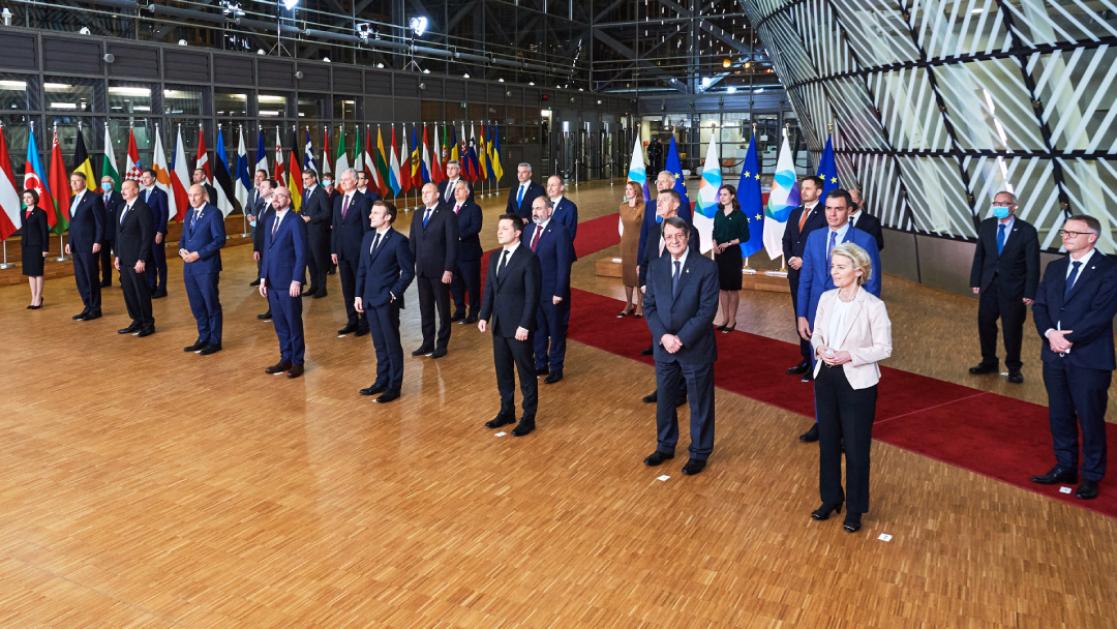 A group of political dignitaries pose for a group photo in EU buildings.